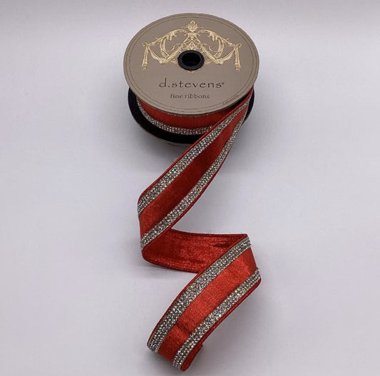 A spool of red ribbon with silver rhinestones is shown against a white background.