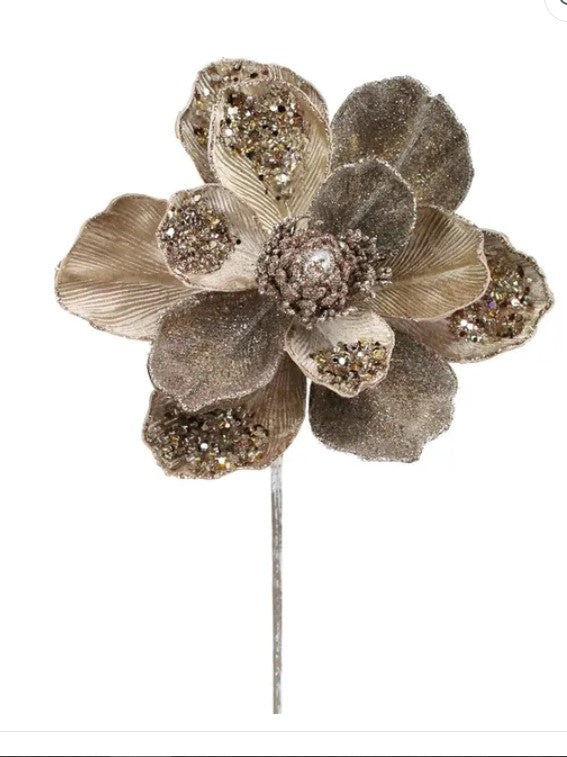 A decorative flower with a gold-colored center and beige petals, adorned with small glittery or metallic elements.