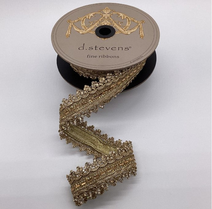 A spool of fine gold ribbon with a decorative trim, placed on a white background.