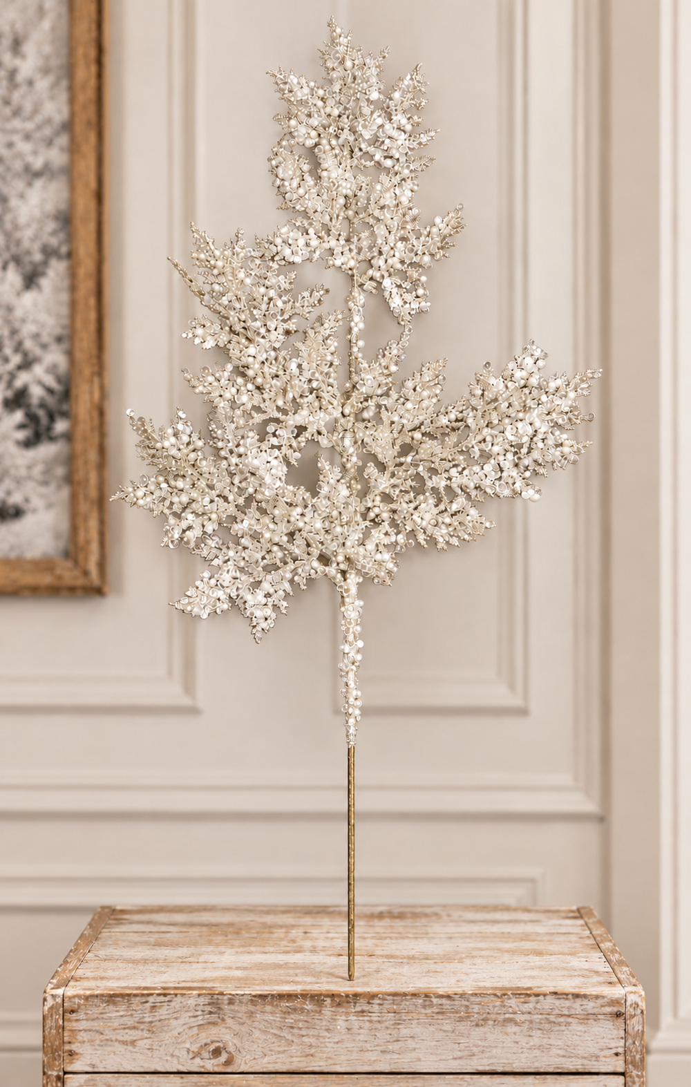 A decorative white branch with small white flowers is displayed on a wooden table.