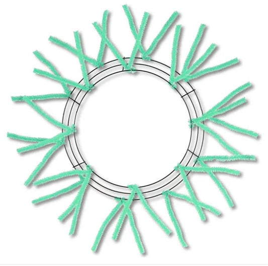 A circular wreath made of green pipe cleaners, with the pipe cleaners arranged in a radial pattern around the center of the wreath.