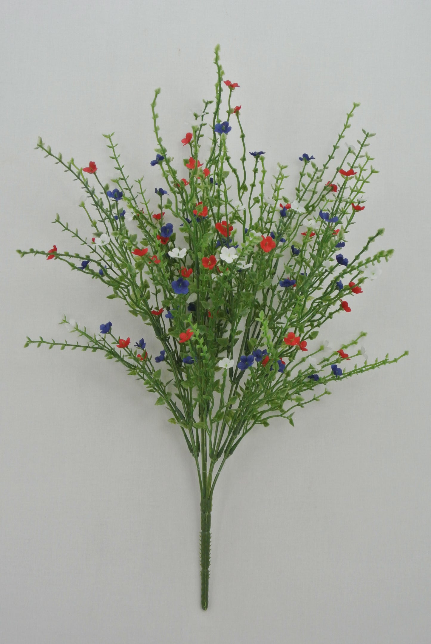 A bouquet of green stems with red, white, and blue flowers arranged in a cluster.