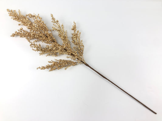 A single golden branch with small, round flowers or berries is shown against a plain white background.