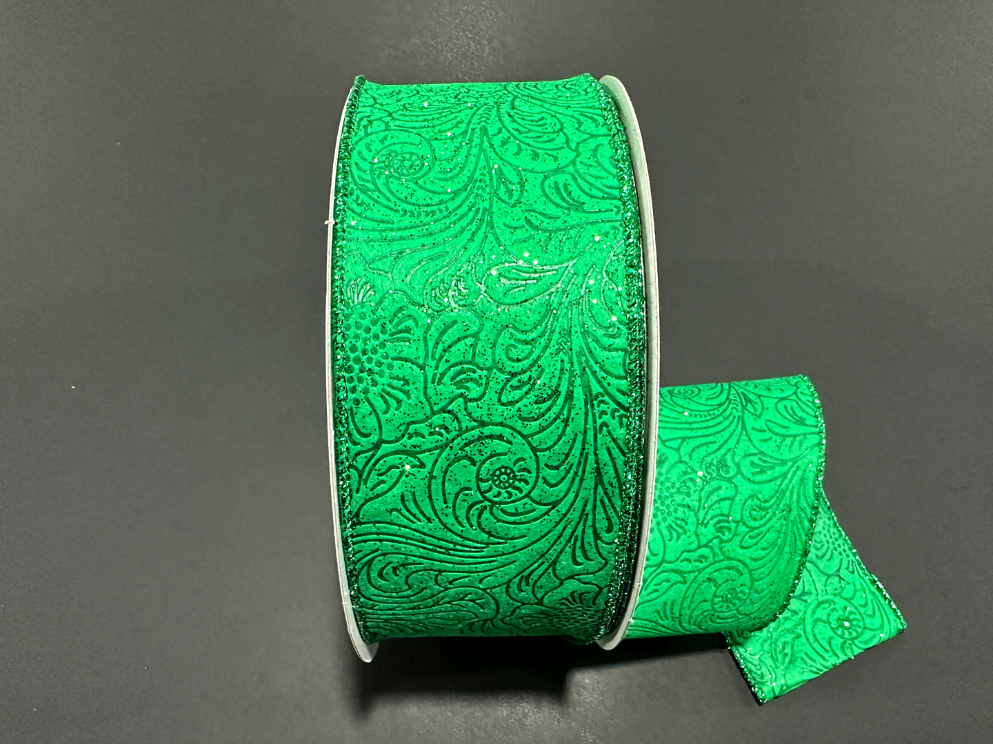 a roll of green sequinized ribbon on a black surface