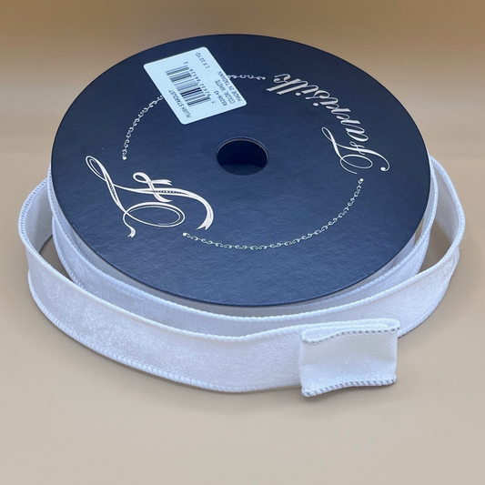 A roll of white ribbon with a black label on it, placed on a beige surface.