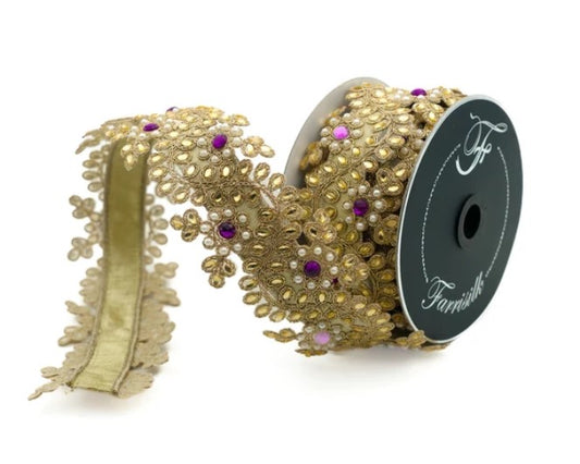 a gold-colored decorative ribbon with a floral pattern and small purple and white embellishments.