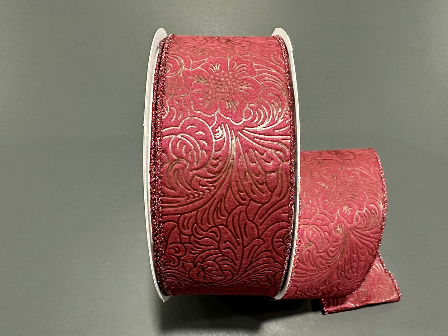 a roll of red ribbon on a gray surface