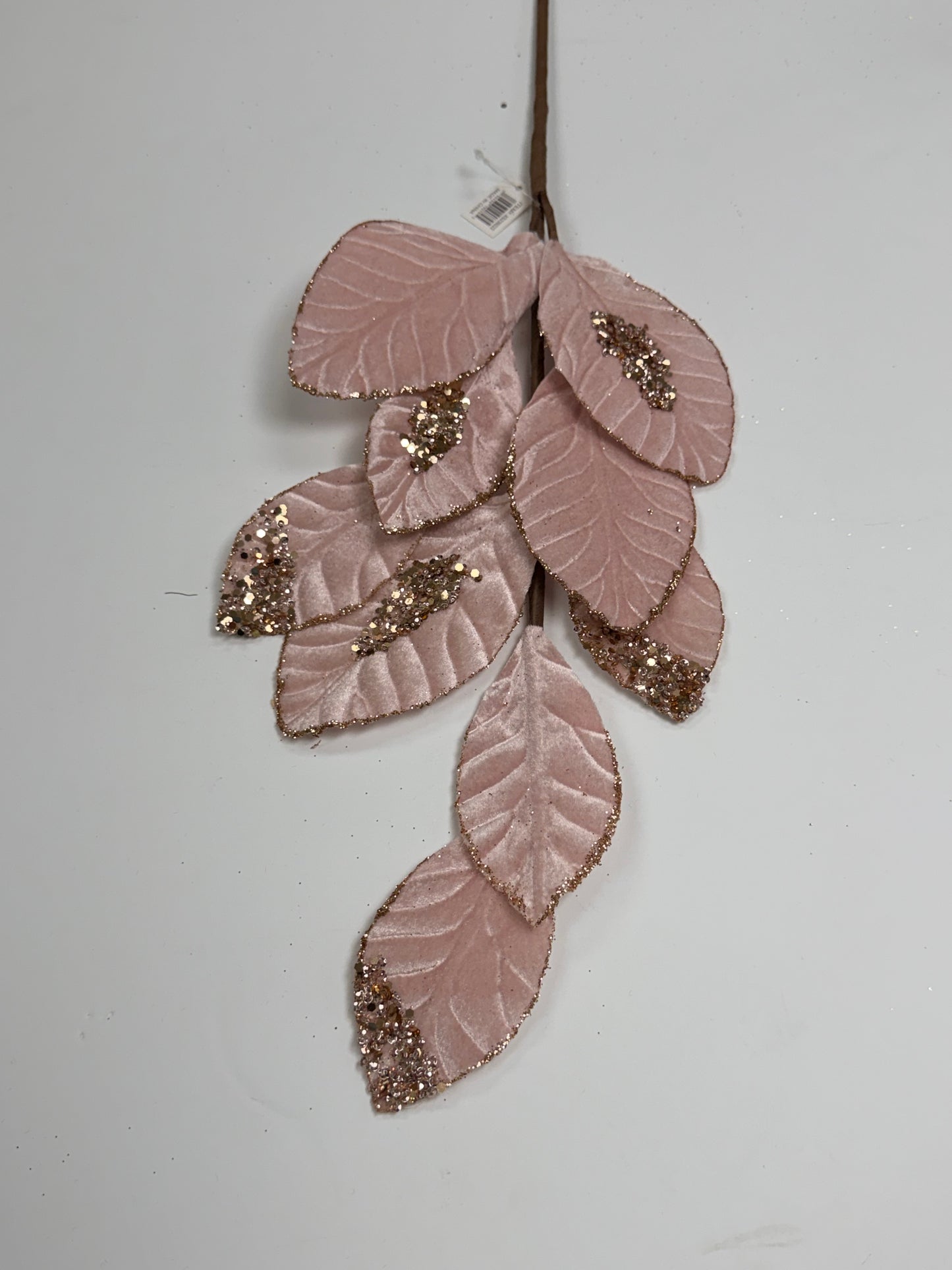 A branch with pink leaves adorned with glittery embellishments.