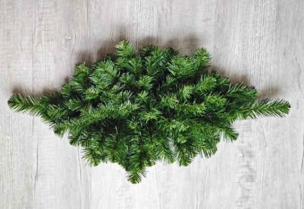 A lush, green pine branch is arranged on a wooden surface, creating a natural and festive display.