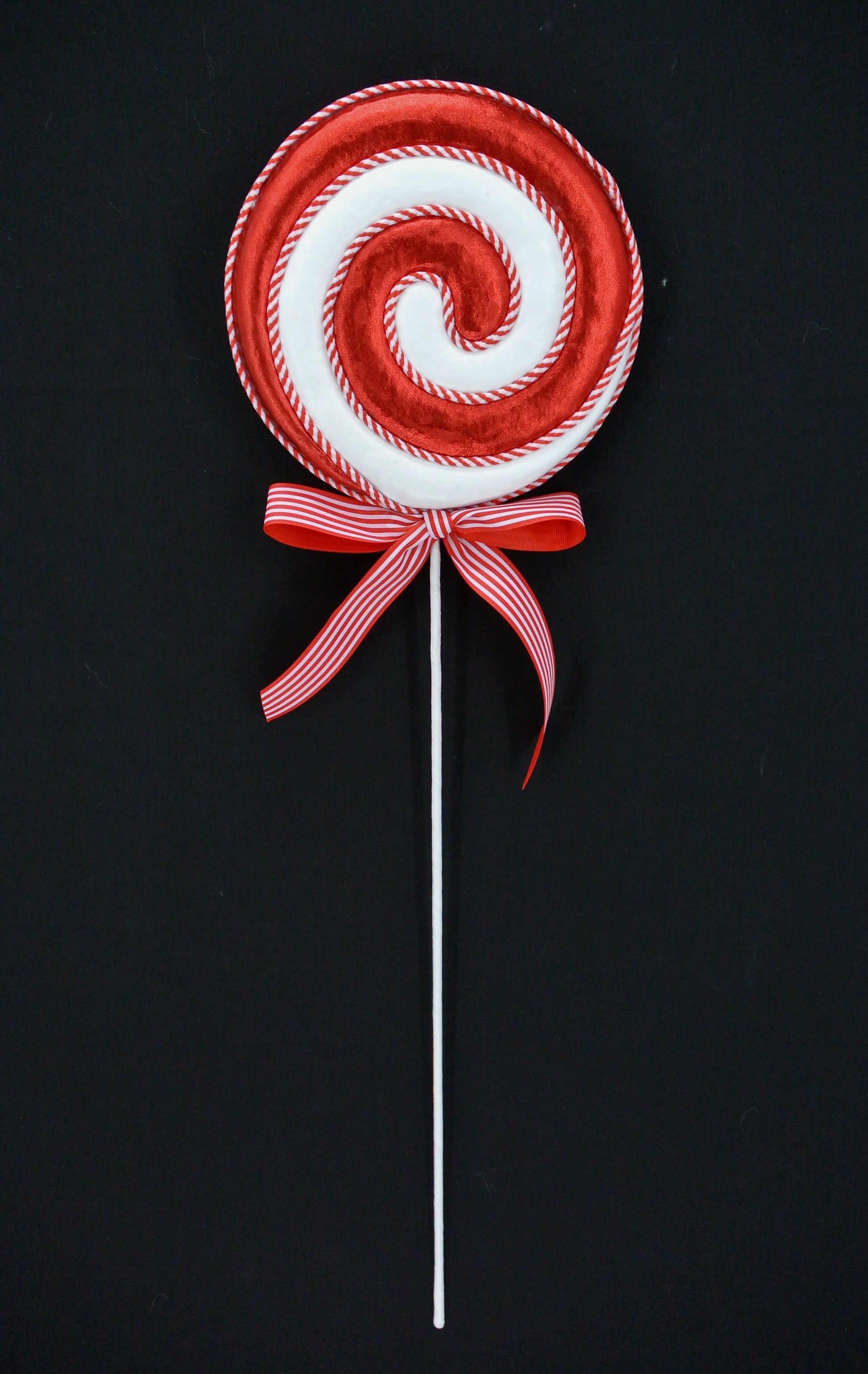 A red and white lollipop with a red ribbon tied around it, against a black background.