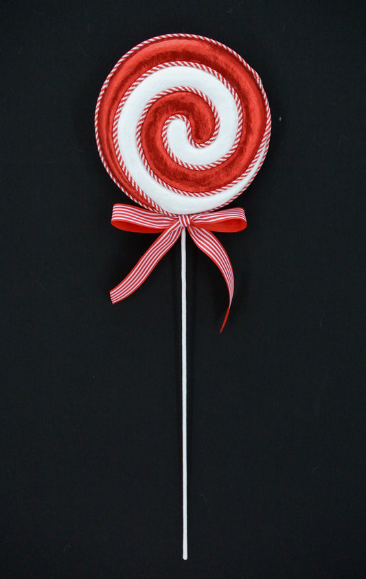 A red and white lollipop with a red ribbon tied around it, against a black background.