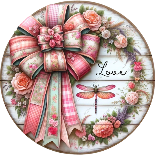 A decorative round wreath made of pink and white ribbons, flowers, and a butterfly.
