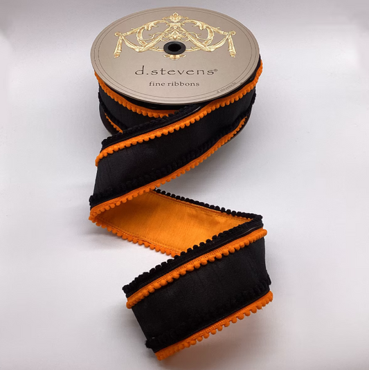 A spool of black and orange ribbons with a decorative label, placed on a white background.