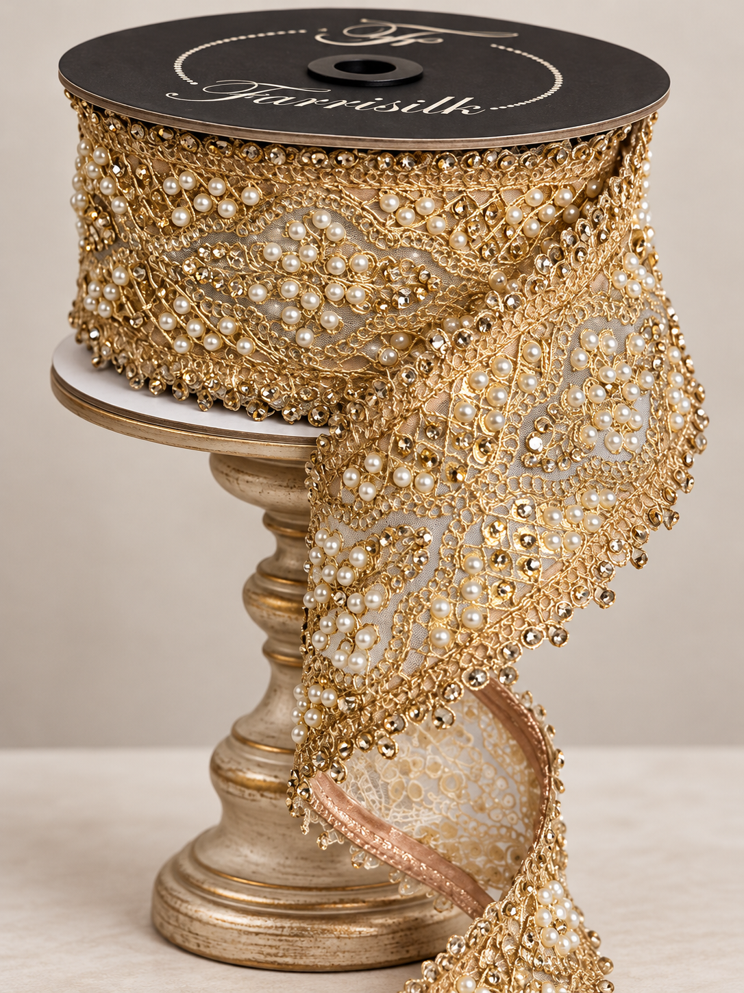 a decorative gold-colored lace trim with a black and white floral pattern, displayed on a gold-colored stand or base.
