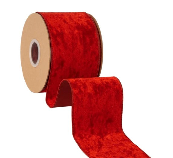 A roll of red velvet ribbon with a white center hole is shown against a white background.