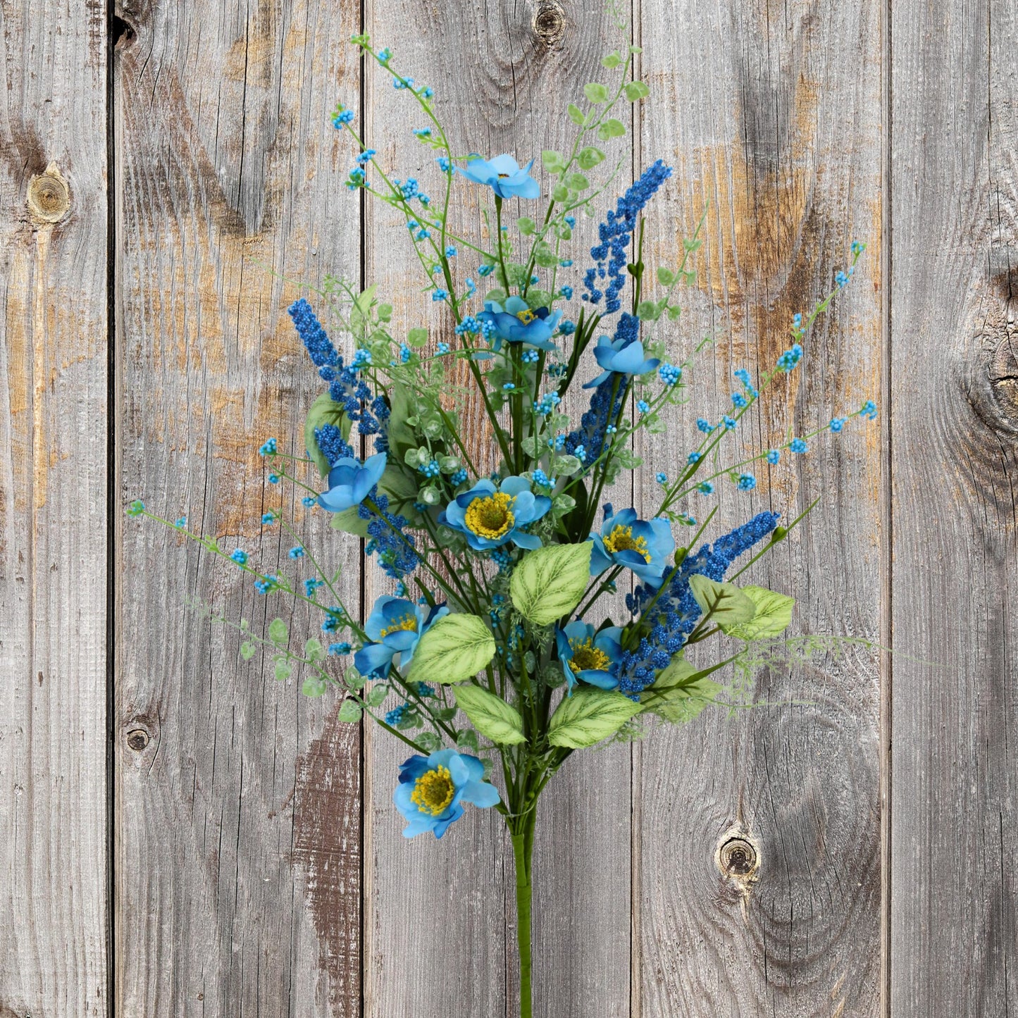 A bouquet of blue flowers and green leaves is displayed against a weathered wooden background.