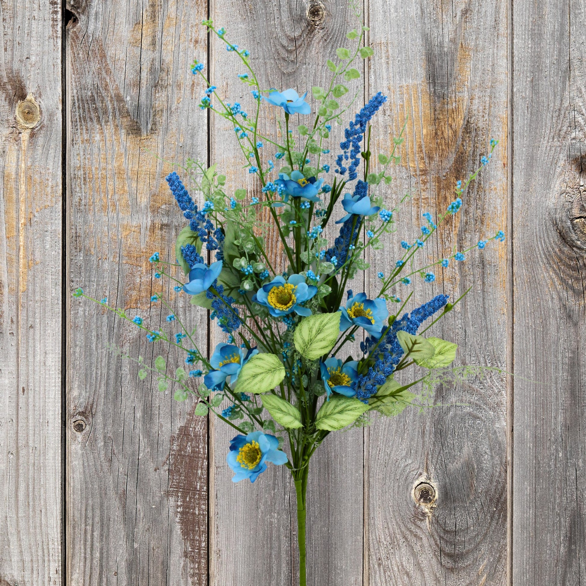 A bouquet of blue flowers and green leaves is displayed against a weathered wooden background.
